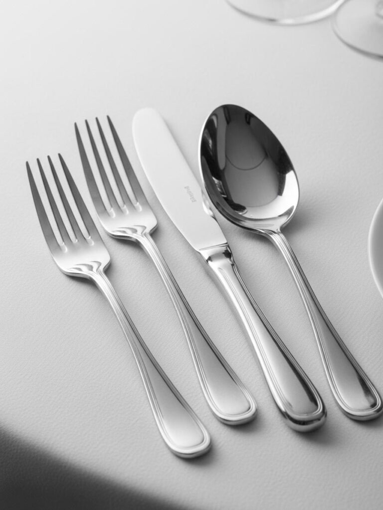 Stainless steel cutlery set arranged on a hotel table — commercial use