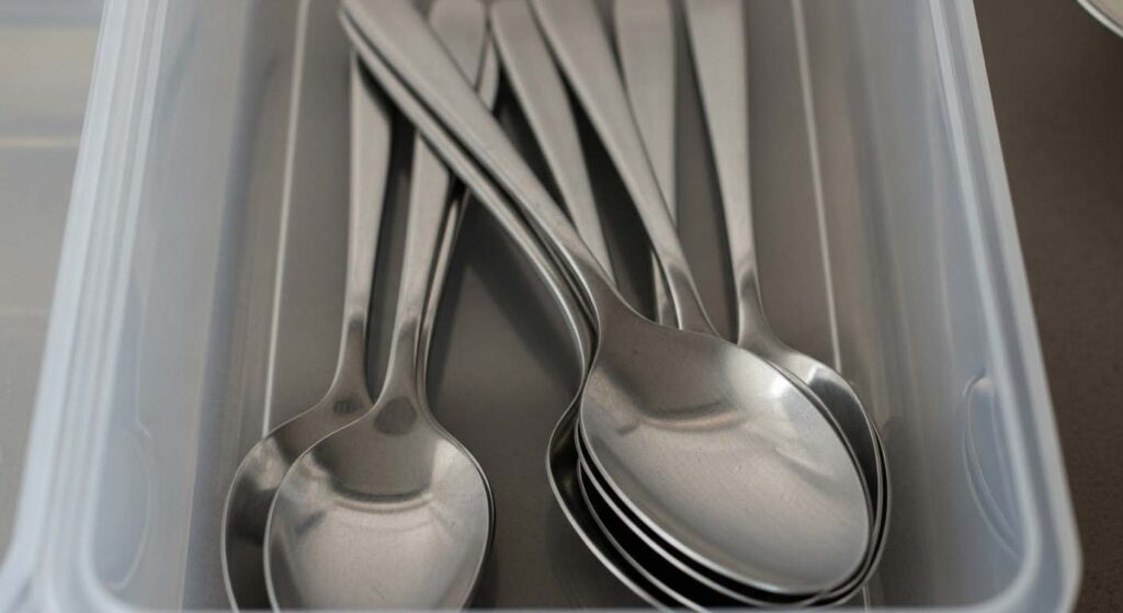 A close-up of a stainless steel spoon with dark, tarnished spots on the bowl