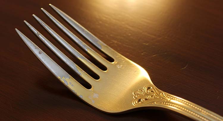 A worn gold electroplated fork with the base metal showing through on the tines and handle