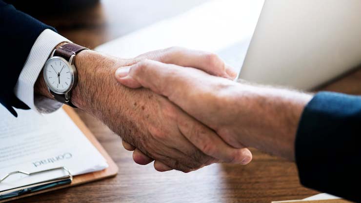 A handshake between a business owner and a factory manager in a clean factory environment