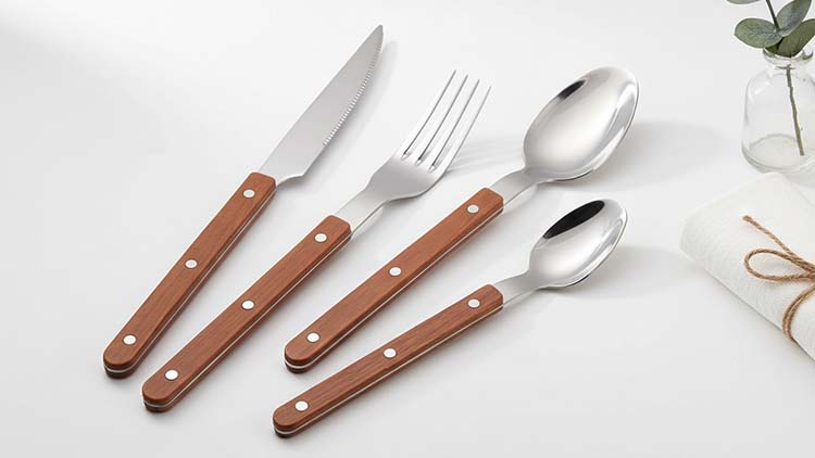 A rustic-styled photo of the W005 cutlery, showcasing both the dark and light faux-wood handle options on a slate or wood surface.
