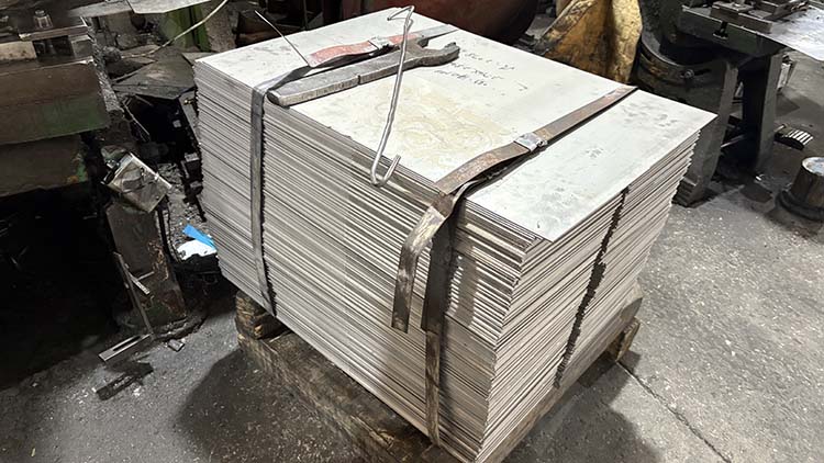 Raw materials like chromium and nickel ingots next to a stainless steel sheet