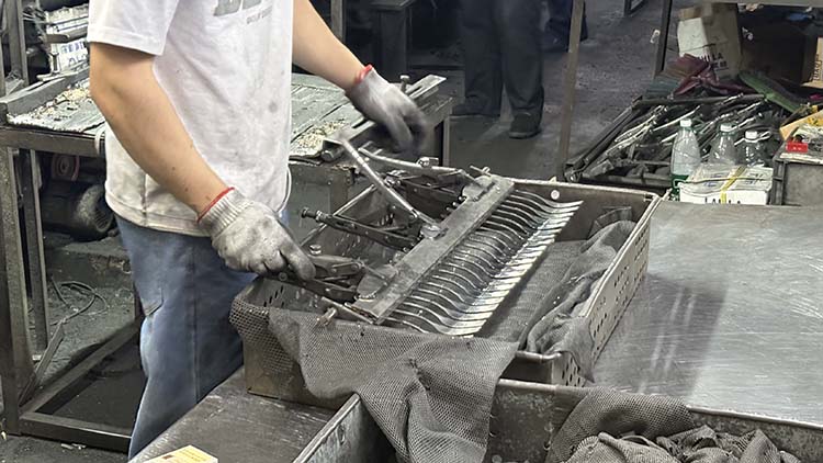 A skilled worker meticulously polishing a fork to a mirror finish in a factory
