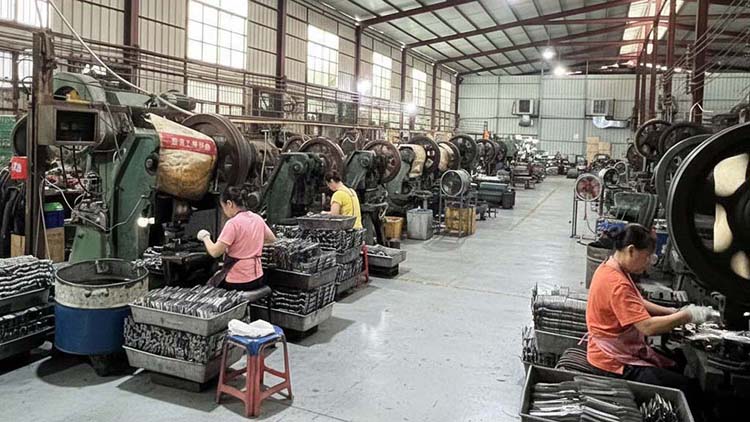 Workers on a busy flatware production line at XR Cutlery factory