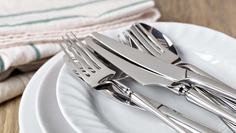 A restaurant owner looking frustrated at a pile of spotted and rusted low-grade forks