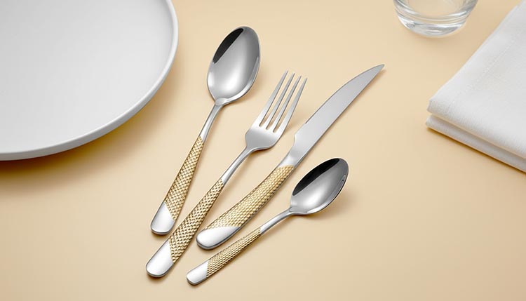 A worker carefully polishing the edges of a hammered fork to ensure it's smooth to the touch