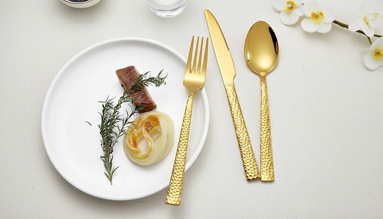 A close-up shot of a finished hammered stainless steel spoon reflecting light from its facets