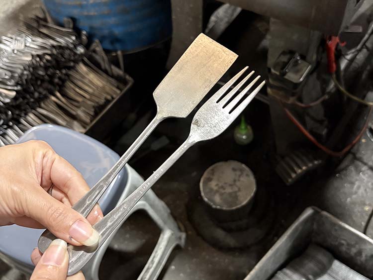 A machine trimming the excess material from a spoon blank