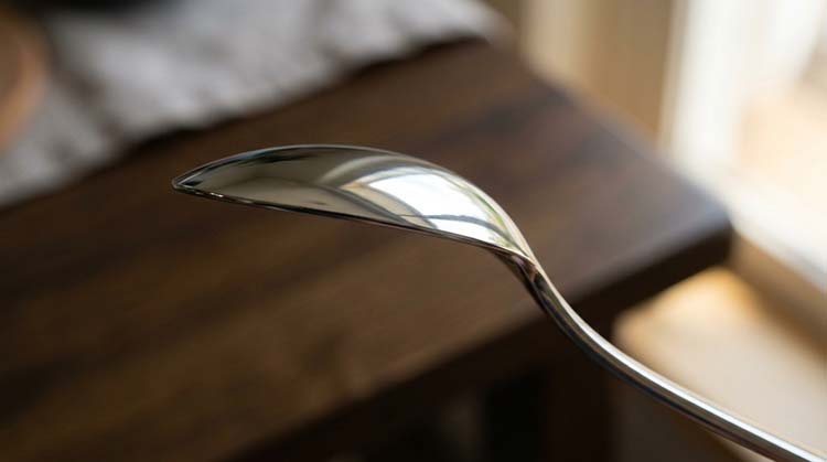 A close-up of a perfectly smooth spoon edge reflecting light