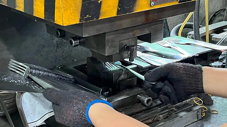 A stamping press forming the bowl of a stainless steel spoon