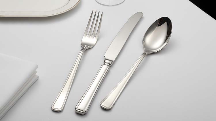 Table setting at a luxury hotel featuring elegant flatware with a mirror-polish smooth handle design