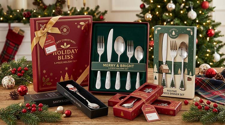 A collection of custom Christmas flatware sets in gold and black, displayed in elegant gift boxes with branded logos.
