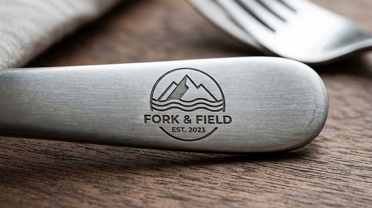 Etching Logos on Stainless Steel Cutlery A close-up of a custom etched logo on the handle of a stainless steel fork, showcasing the clean lines and metallic texture of the etching.
