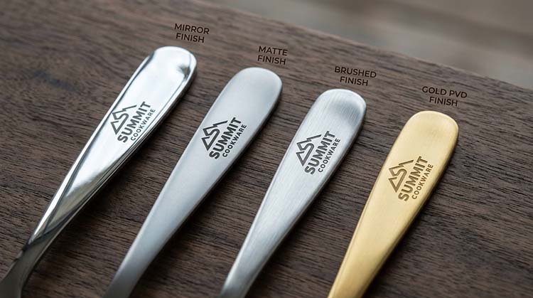 How Surface Finish Affects Etched Logos Four stainless steel spoon handles showing the same etched logo on different finishes: mirror, matte, brushed, and black PVD.