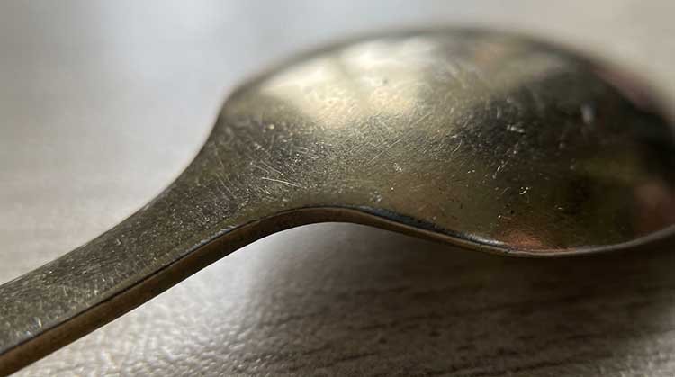 A magnified image showing scratches on a poorly coated piece of cutlery.
